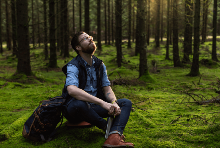 Ein Mann sitzt im Fichtenwald