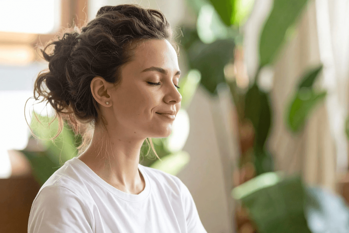 Eine junge Frau, die mit geschlossenen Augen in Meditation verweilt
