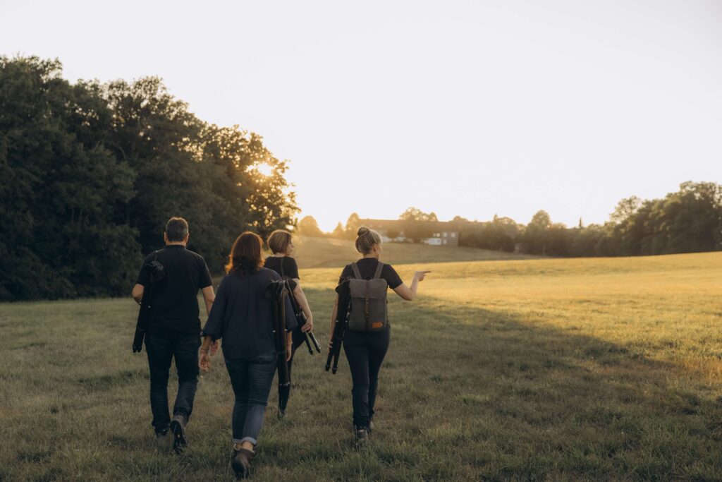 Kerstin Rubel geht mit einer Wandergruppe über eine offene Wiese.